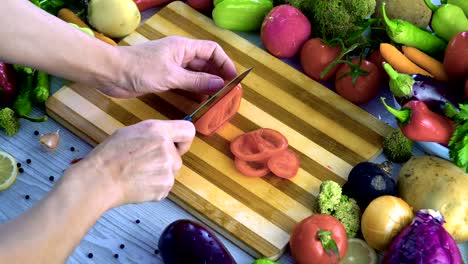 Man-is-cutting-vegetables-in-the-kitchen,-slicing-tomato