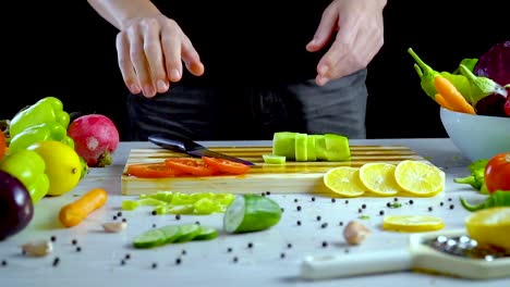 Man-is-cutting-vegetables-in-the-kitchen,-slicing-cucumber
