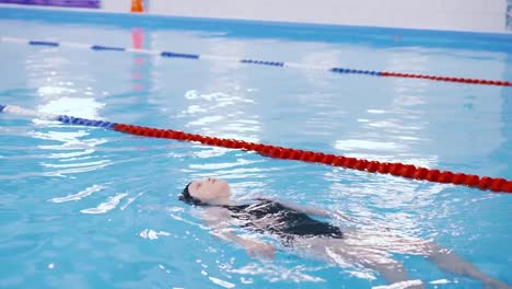 clases-de-natación-para-niños-en-la-piscina---hermosa-chica-de-piel-clara-nada-en-el-agua