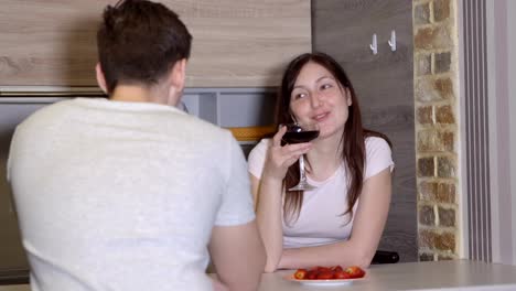 Young-couple-at-a-table-with-wine-and-strawberries.-Romantic-evening