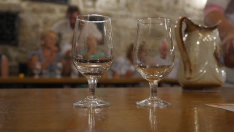 Degustación-de-vinos-en-la-sala-de-degustación.-Excursión-alrededor-de-la-bodega-de-la-Crimea.-Bakaly-stand-sobre-la-mesa.-Vino-se-vierte-en-un-plato-de-cristal.-Sommelier-extiende-su-mano-a-su-vaso.-VALLE-SOLEADO