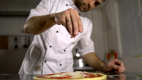 The-chef-sprinkles-spices-on-the-finished-pizza-in-the-kitchen