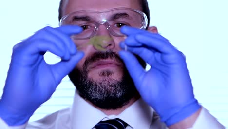 Biologist-examines-sample.-Science,-biology,-ecology.-Professional-scientist-wearing-protective-mask-working-with-herb-samples-in-his-laboratory.-Male-scientist-looking-at-plant-leaf-in-glass-slide.