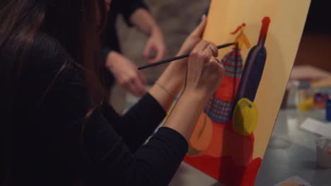 Young-woman-artist-is-painting-picture-on-canvas-in-art-studio