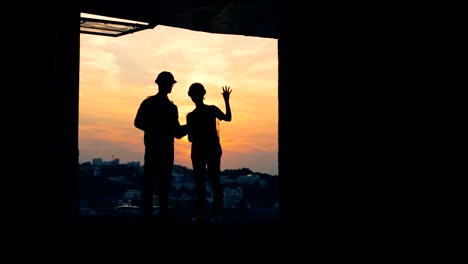 Architects-standing-in-unfinished-building-on-a-sunset-background.