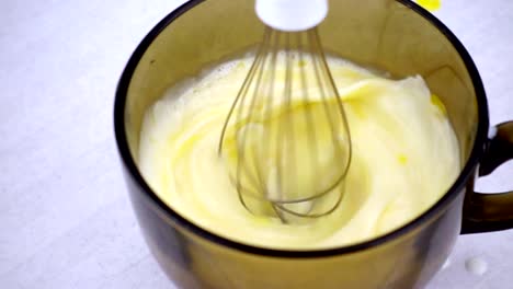 Electric-mixer-whisk-the-eggs-in-a-bowl-with-milk.-Working-mixer-in-slow-motion.