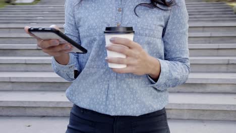 Ansicht-Frau-mit-Kaffee-in-der-hand-mit-Smartphone-hautnah.