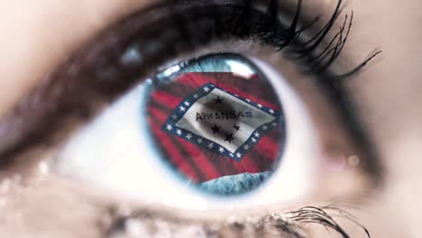 Woman-blue-eye-in-close-up-with-the-flag-of-Arkansas-state-in-iris,-united-states-of-america-with-wind-motion.-video-concept