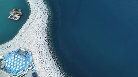 Ansicht-von-oben-auf-schöne-weiße-Dock-mit-weißen-Felsen-und-eine-Yachtauf-blauem-Wasser-Hintergrund,-Limassol,-Zypern