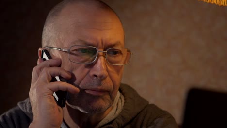 older-man-using-a-laptop-and-talking-on-the-phone