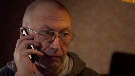 older-man-using-a-laptop-and-talking-on-the-phone