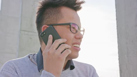 Un-hombre-joven-hablando-por-un-teléfono-exterior