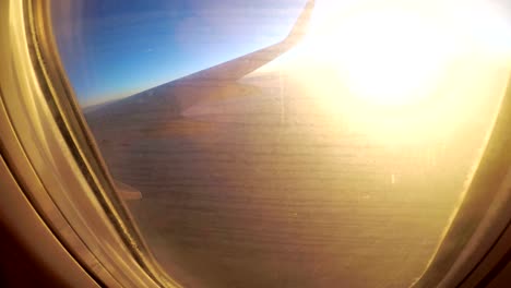 Blick-aus-dem-Fenster-eines-Passagier-Flugzeug-während-des-Sonnenuntergangs-auf-eine-Landschaft-und-Horizont