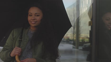 Eine-schöne-junge-Frau-stand-neben-einem-Gebäude-einen-Regenschirm-mit-gedrückter-mittlerer-Schuss.-Sie-dann-lacht-und-geht-weg