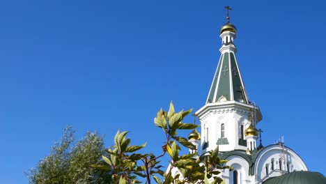 Dome-of-the-Church-and-leaves.-The-silhouette-of-the-cross-and-church-bell-tower-in-sunrise.-An-autumn-windy-day-shakes-the-leaves-of-the-trees.