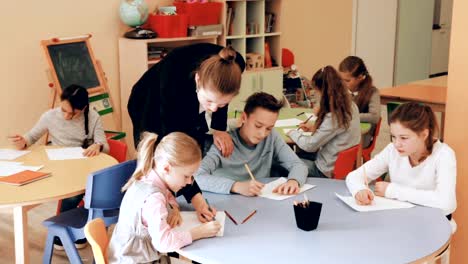 niños-y-niñas-sentados-y-profesor-de-dibujo-de-ayuda