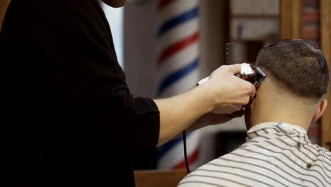Stylist-makes-haircut-to-a-young-man-with-electric-razor