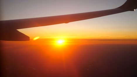 Blick-vom-Flugzeugfenster-zu-schönen-Sonnenaufgang-oder-Sonnenuntergang.-Flügel-des-Flugzeugs-und-Wolke-Himmel.-Konzept-der-Reisen-oder-Tourismus.-Nahaufnahme-Seitenansicht