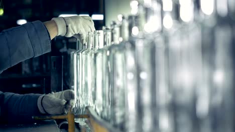 A-factory-worker-examines-bottles'-neck-on-a-conveyor-at-a-plant.-4K.