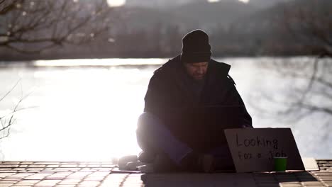 Homeless-bearded-male-begging-and-using-laptop