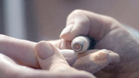 Extreme-Close-up,-maestro-de-forma-de-manicura-da-de-Noggy-en-la-mano-de-una-mujer-con-la-ayuda-de-una-herramienta-de-pulido