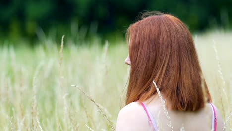 Red-haired-woman-looks-around-to-camera-outdoors,-slow-motion-beautiful-lady