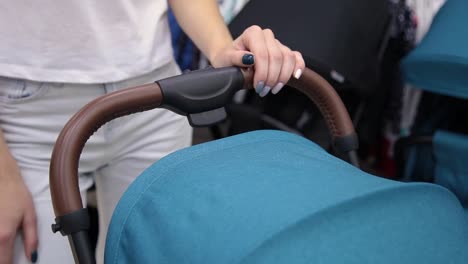 A-woman-is-holding-a-baby-carriage-by-her-hands,-close-up