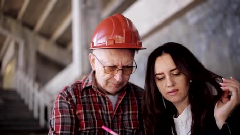 El-ingeniero-de-la-mujer-y-el-capataz-en-casco-compare-adquirida-para-la-construcción-de-la-declaración-y-confirman-la-fecha-de-entrega-del-objeto.