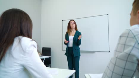 Young-Caucasian-teacher-near-whiteboard-coaching-college-students-in-classroom