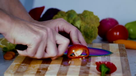 Man-is-cutting-vegetables-in-the-kitchen,-slicing-red-bell-pepper-in-slow-motion