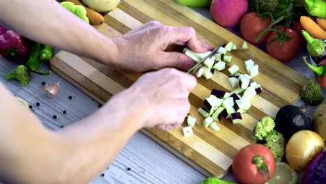 Man-is-cutting-eggplant-on-cutting-board-in-the-kitchen