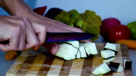 Man-is-cutting-eggplant-on-cutting-board-in-the-kitchen