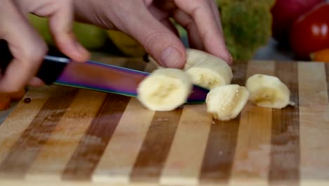 Man-is-cutting-banana-on-cutting-board,-close-up-footage