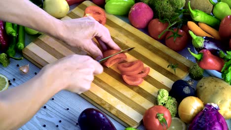 El-hombre-es-vegetales-de-corte-en-la-cocina,-cortar-el-tomate-en-cámara-lenta