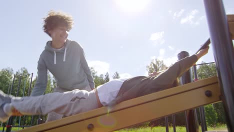 Mother-Teaching-Little-Son-to-Do-Leg-Raises-on-Outdoor-Workout-Playground