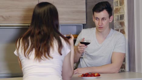 Young-man-and-woman-at-a-table-with-wine-and-strawberries.-Romantic-evening