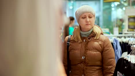 A-middle-aged-woman-in-a-winter-coat-and-a-hat-goes-to-a-children's-clothing-store.-Fits-the-camera.