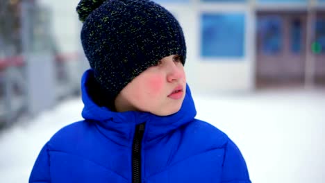 Boy-teenager-in-blue-down-jacket-lost-in-the-city.-He's-at-the-train-station,-looks-around.