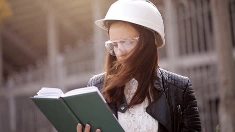 Die-Frau-Student-Architekt-auf-der-Baustelle-prüft-die-technischen-Unterlagen-und-macht-Notizen-in-seinem-Notizbuch