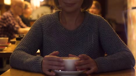 Pretty-young-woman-drinking-cappuccino-sitting-in-restaurant,-hot-beverage