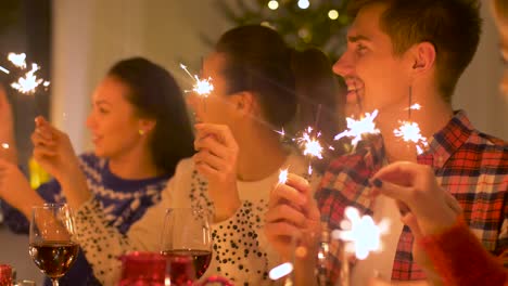 Glückliche-Freunde-mit-Wunderkerzen,-die-Weihnachts-Dinner-zu-Hause