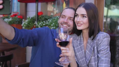 Feliz-pareja-con-vino-tomando-fotos-en-el-teléfono-en-el-restaurante