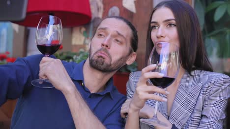 Feliz-pareja-con-vino-tomando-fotos-en-el-teléfono-en-el-restaurante