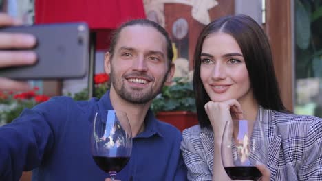 Feliz-pareja-con-vino-tomando-fotos-en-el-teléfono-en-el-restaurante