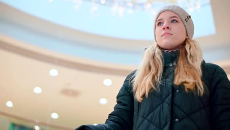 Young-attractive-girl-riding-an-escalator-in-the-mall.-Down