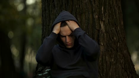 Depressed-man-sitting-under-tree-in-park,-unemployment-problem,-difficulties