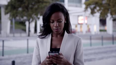 Serious-African-American-woman-using-smartphone-in-city