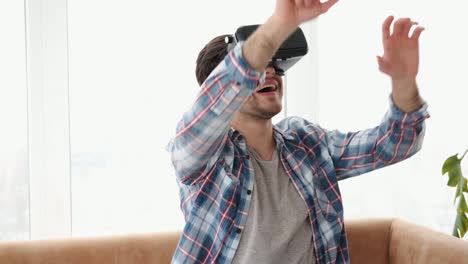 Man-playing-game-with-virtual-reality-goggles-at-home