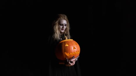 Halloween-Bild.-Junge-Hexe-in-schwarzer-Kleidung-hält-Kürbis-in-ihren-Händen.