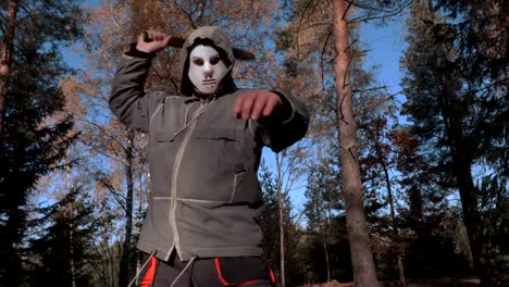 Camera-focusing-on-man-in-scary-Halloween-mask-who-using-machete